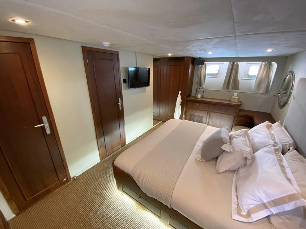 A cozy stateroom with a comfortable bed and elegant wooden furnishings. aboard STALCA Yacht for Sale