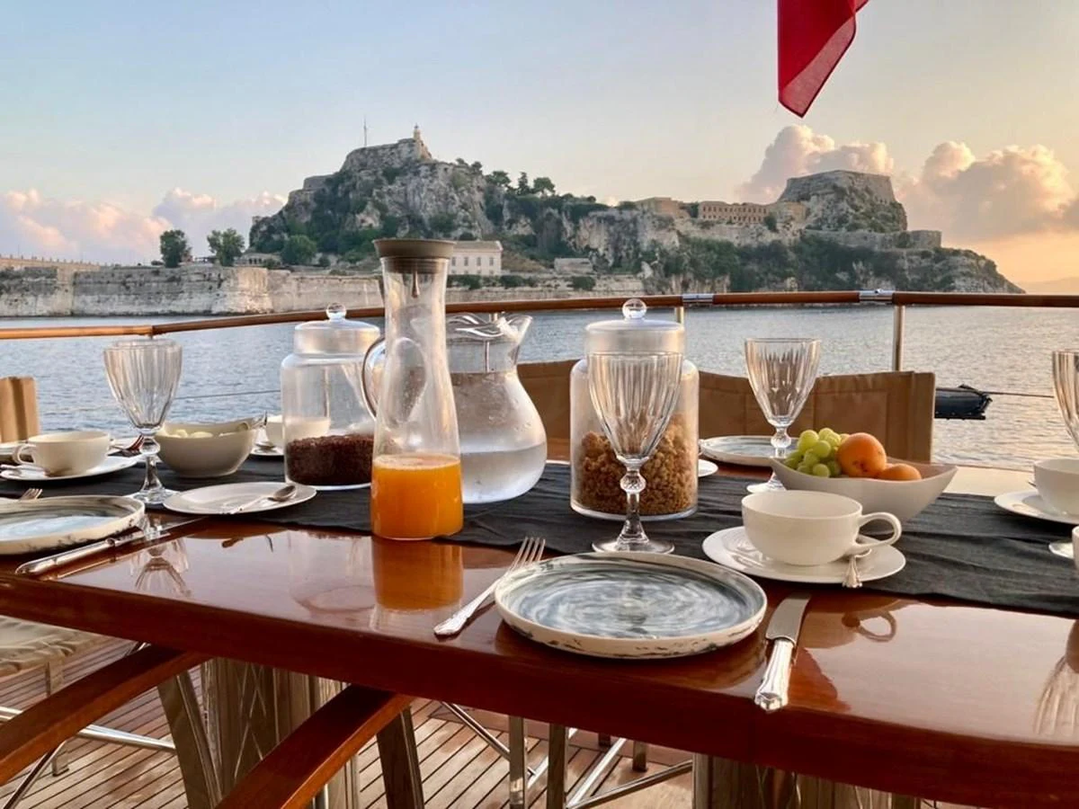 An elegant dining setup on the yacht's deck with a scenic view of the coastline. aboard STALCA Yacht for Sale