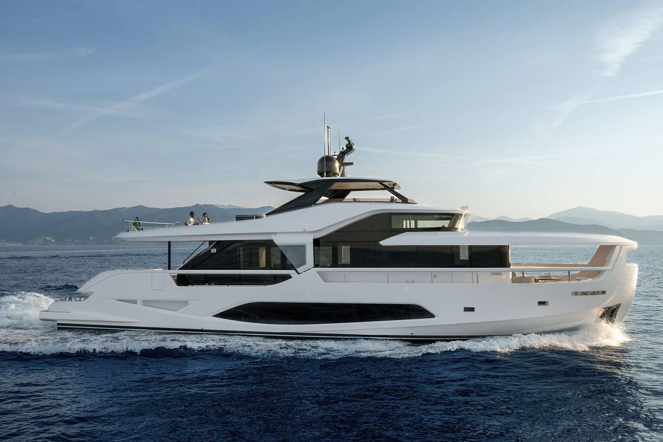 A sleek and modern yacht cruising on calm waters with a stunning backdrop of mountains. aboard INFYNITO 80 Yacht for Sale