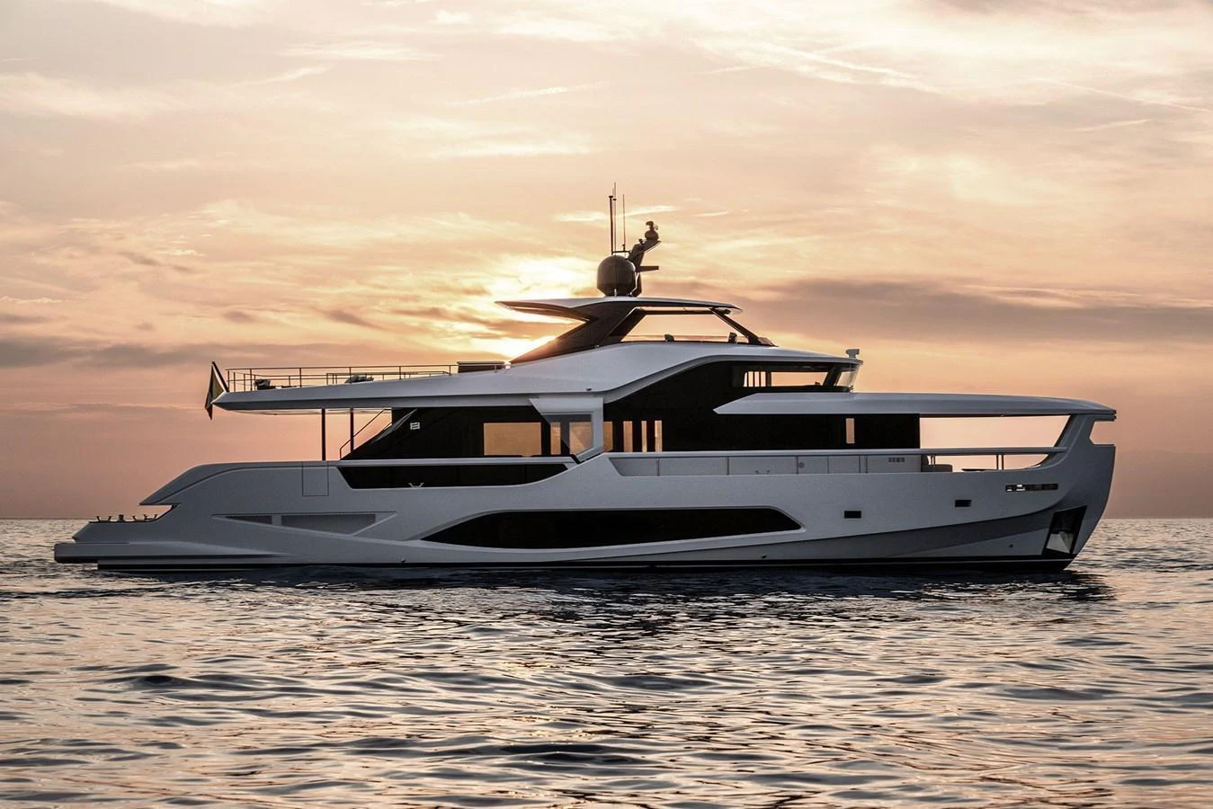 A sleek and modern yacht cruising at sunset, showcasing its elegant profile and luxurious design. aboard INFYNITO 80 Yacht for Sale