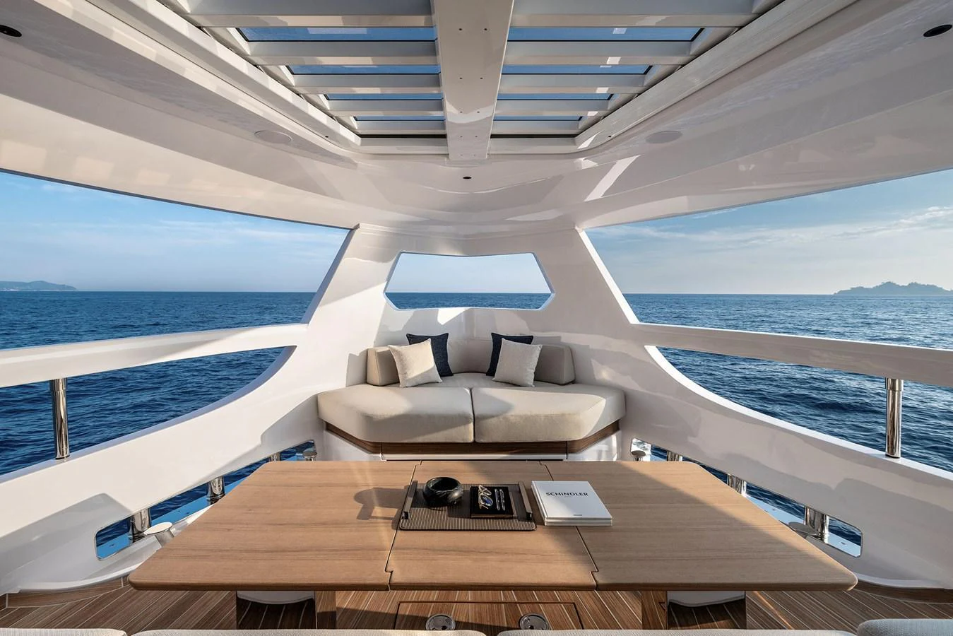 The salon offers panoramic ocean views with a comfortable seating area and a sleek wooden table. aboard INFYNITO 80 Yacht for Sale