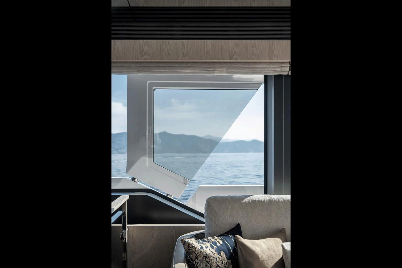 A serene view of the sea through a large window from the yacht's interior, complemented by a cozy seating area. aboard INFYNITO 80 Yacht for Sale