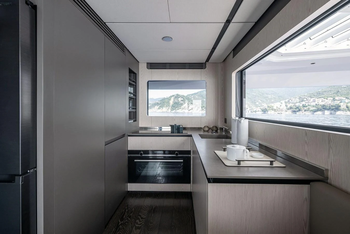 The modern galley features sleek cabinetry and expansive windows with a stunning sea view. aboard INFYNITO 80 Yacht for Sale