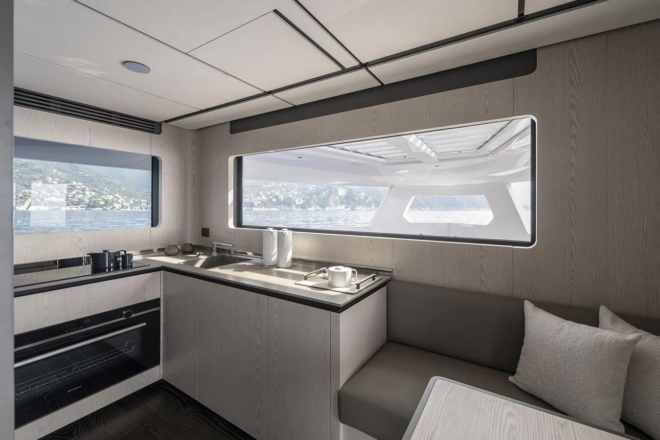 The yacht's galley features modern appliances and a comfortable dining area with panoramic windows offering stunning sea views. aboard INFYNITO 80 Yacht for Sale