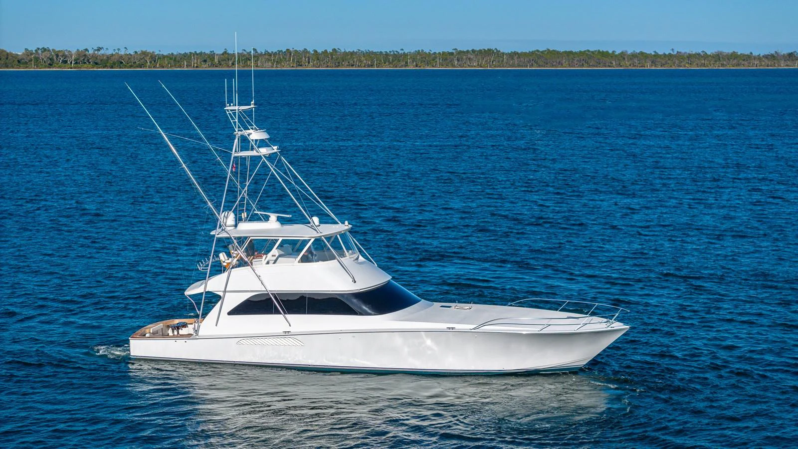 A sleek white yacht cruises on calm blue waters with a clear sky in the background. aboard FIRST BITE Yacht for Sale