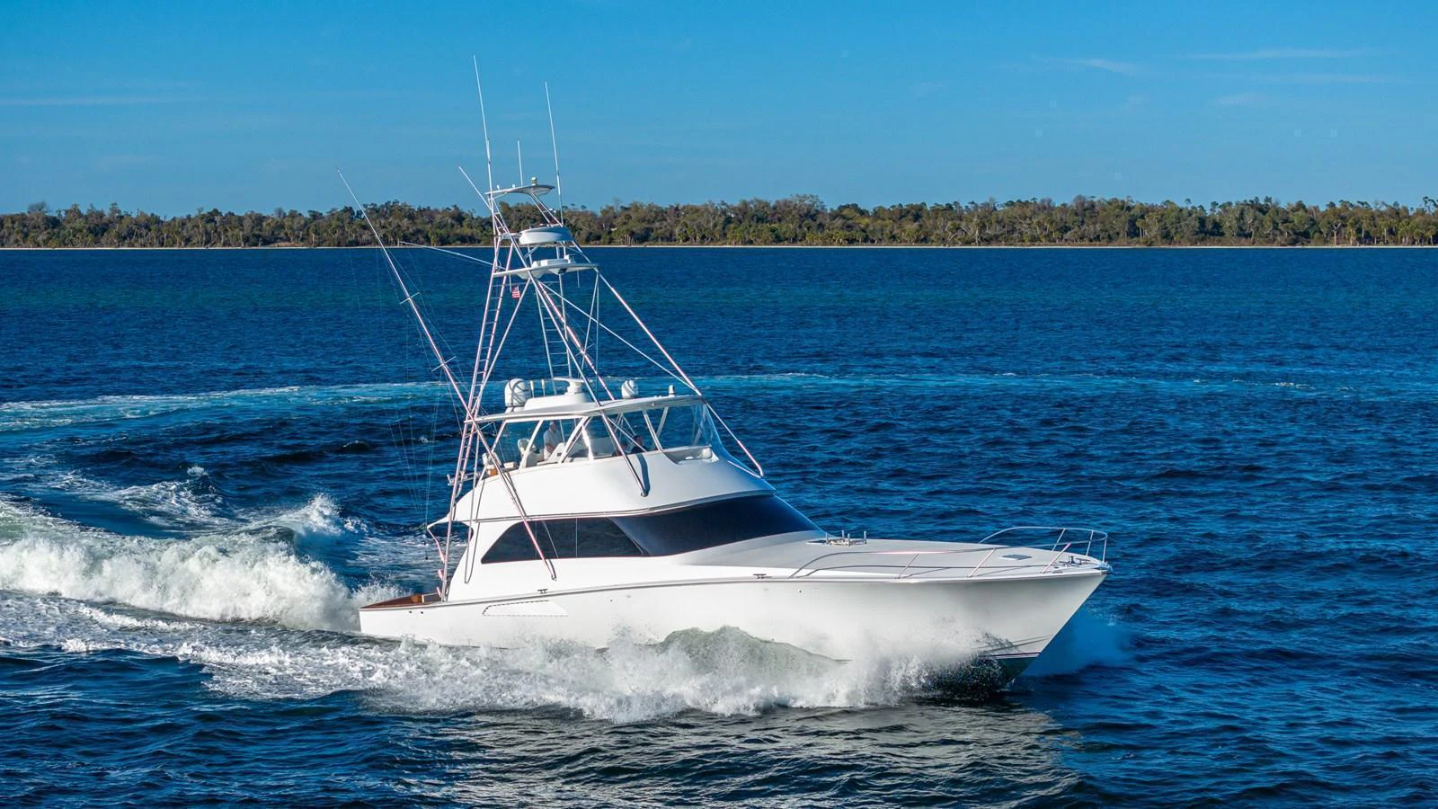 A sleek yacht cruises swiftly through clear blue waters on a sunny day. aboard FIRST BITE Yacht for Sale