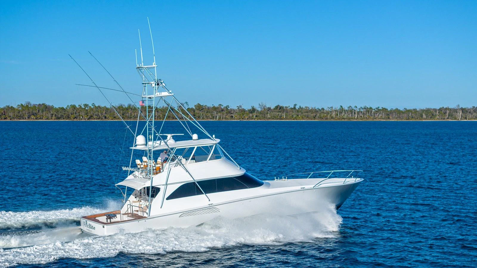 A sleek yacht cruises swiftly on calm blue waters under a clear sky. aboard FIRST BITE Yacht for Sale