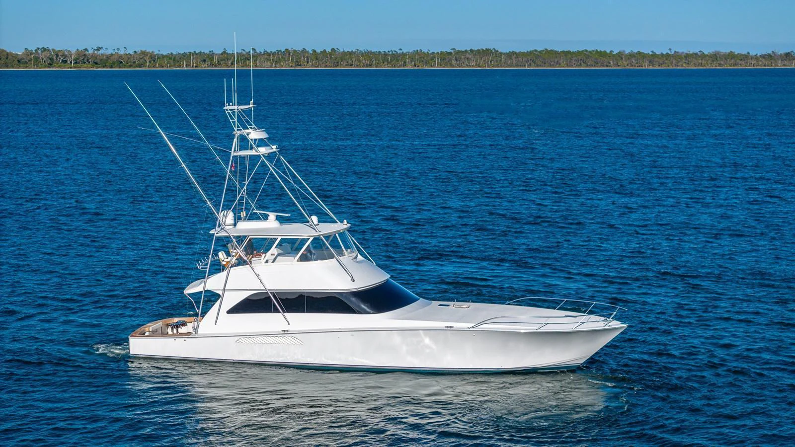 A sleek white yacht glides gracefully on calm blue waters under a clear sky. aboard FIRST BITE Yacht for Sale