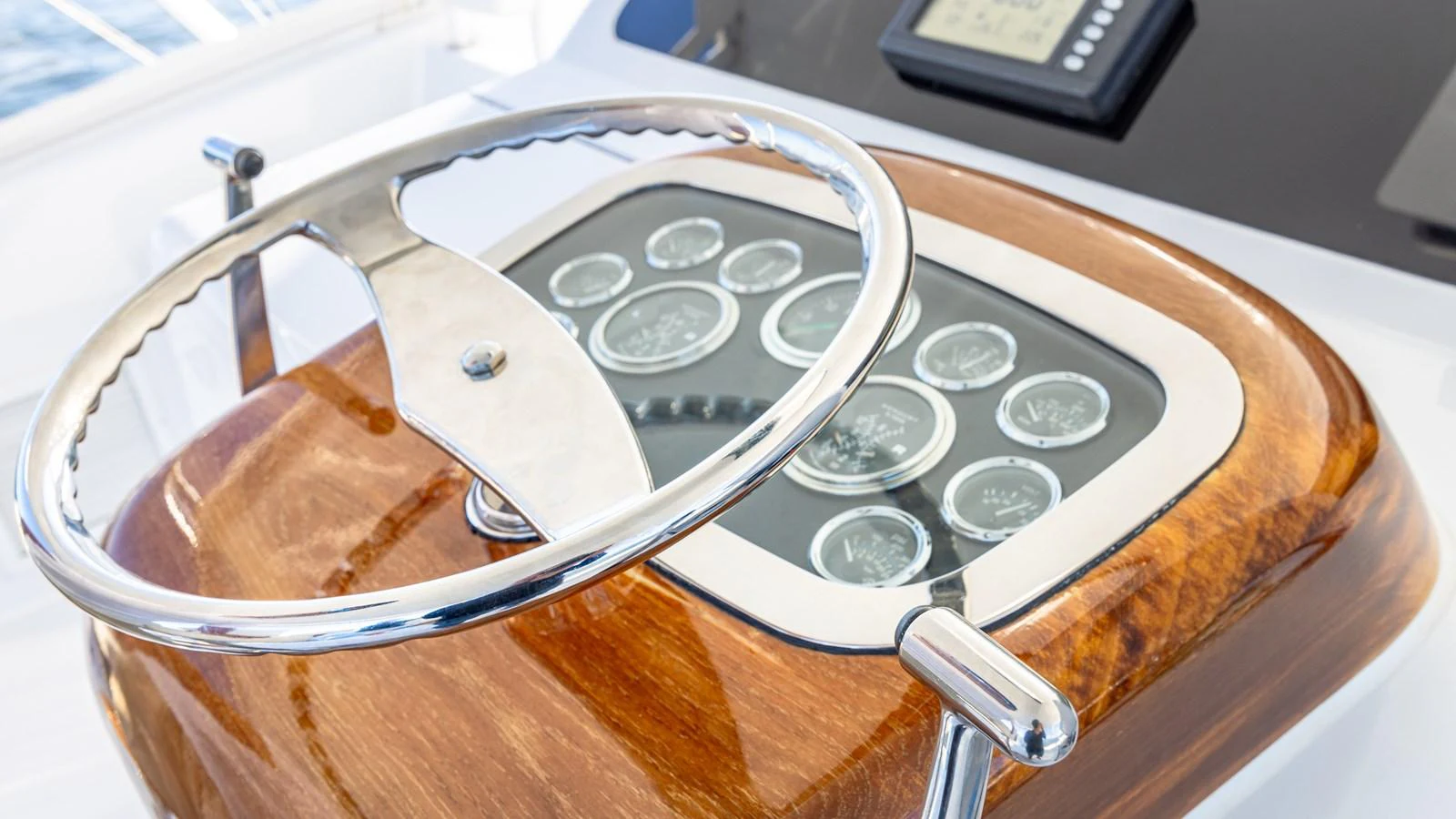 The image showcases a polished wooden helm with a stainless steel steering wheel and an array of gauges. aboard FIRST BITE Yacht for Sale