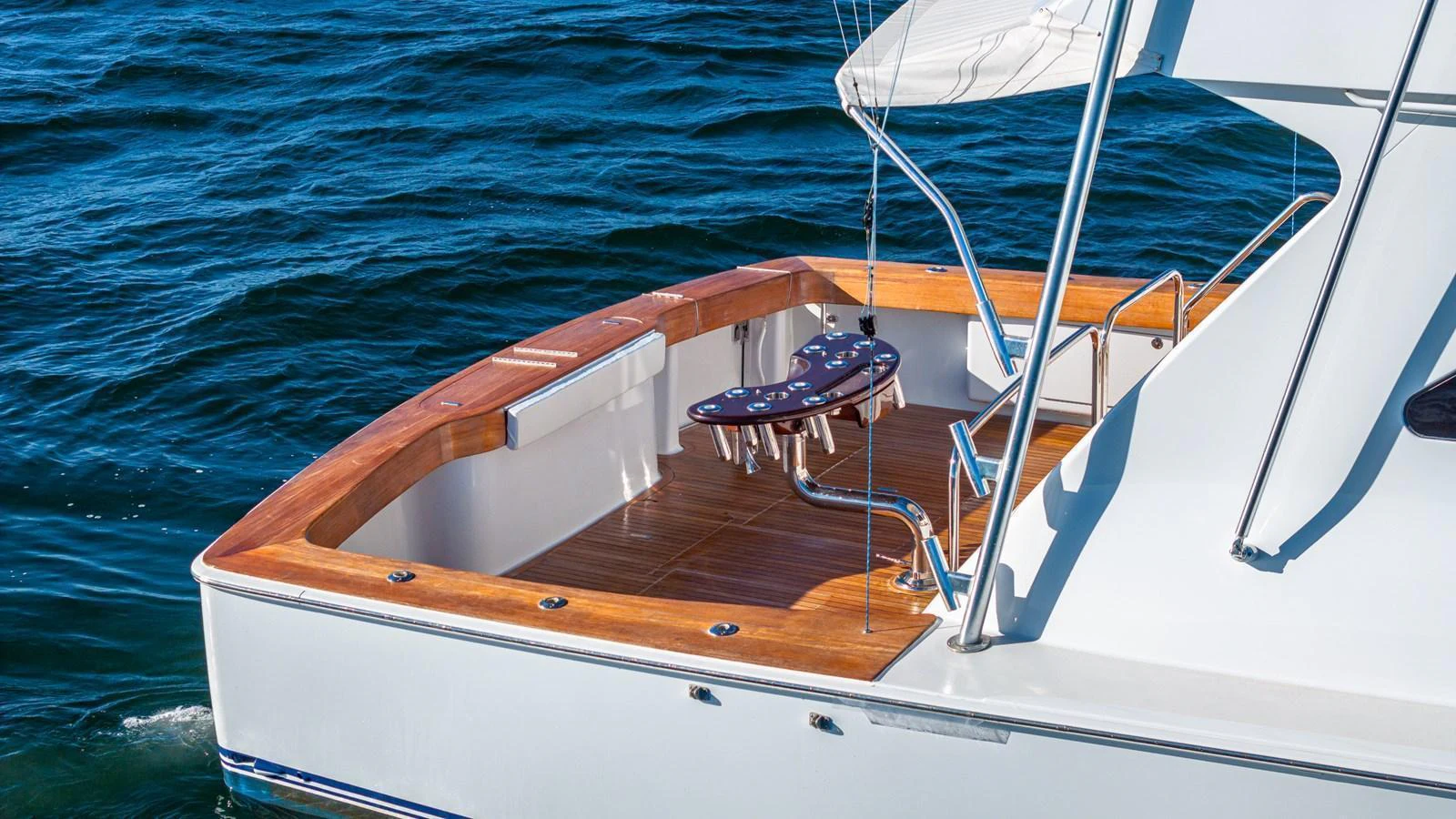 The yacht's aft deck features a sleek wooden finish and a stylish seating area, perfect for relaxation. aboard FIRST BITE Yacht for Sale