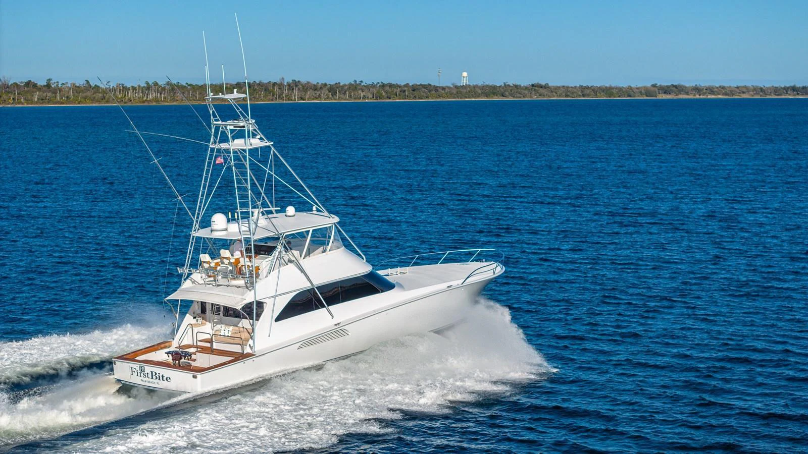 A sleek yacht cruises swiftly on calm blue waters under a clear sky. aboard FIRST BITE Yacht for Sale