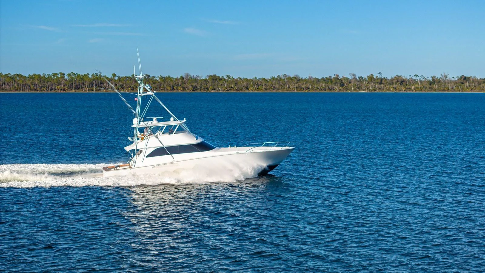 A sleek yacht cruises swiftly across calm blue waters under a clear sky. aboard FIRST BITE Yacht for Sale
