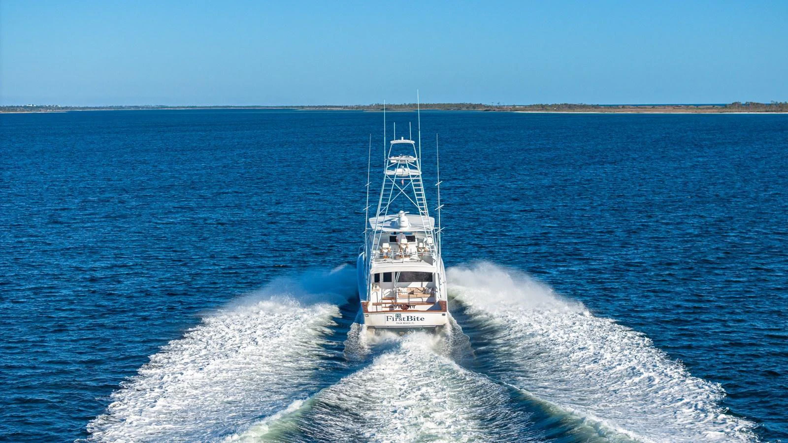 A yacht speeds away on open water, leaving a trail of white wake behind. aboard FIRST BITE Yacht for Sale
