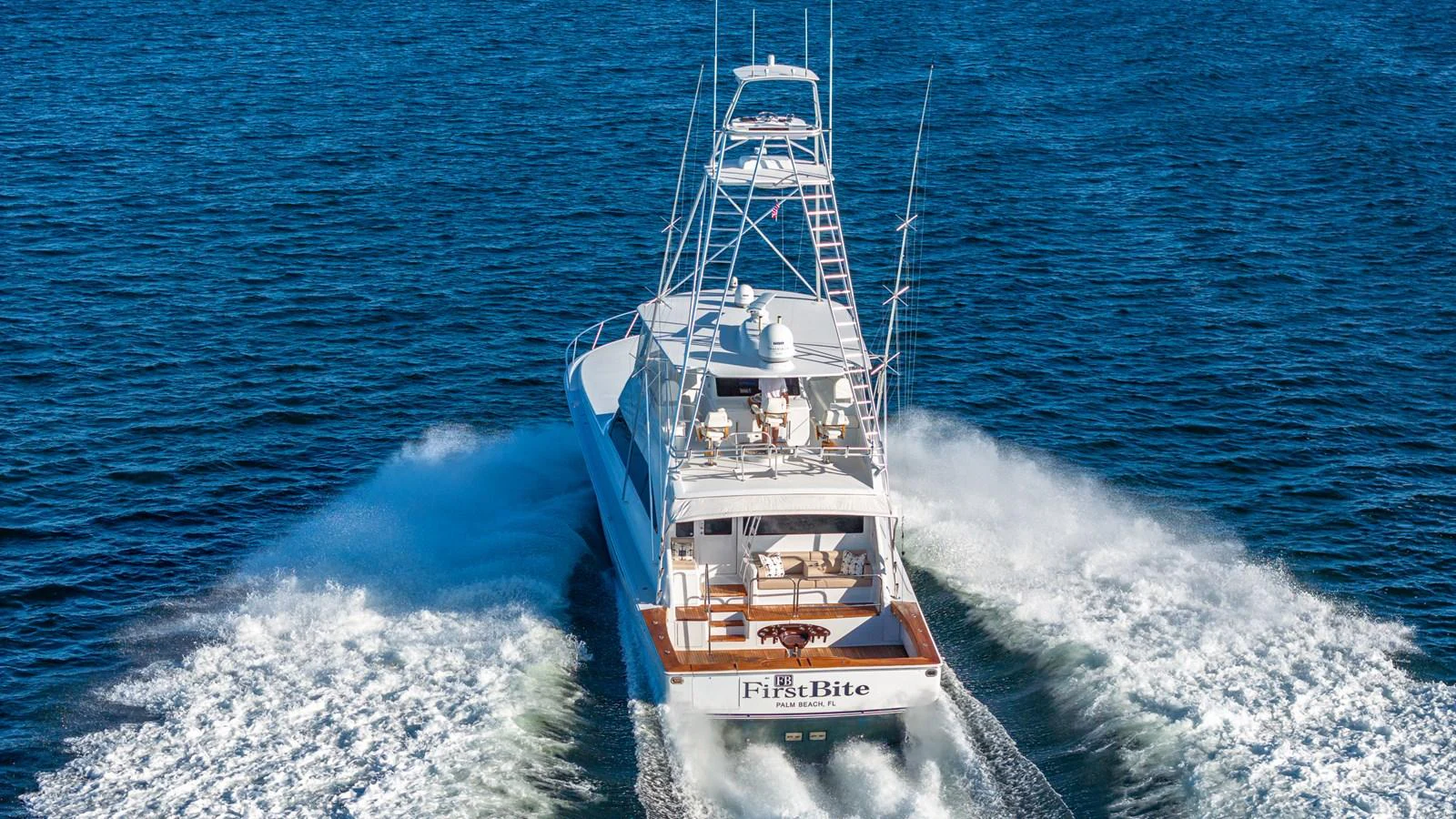 A sleek yacht cruises powerfully through the open water, leaving a trail of white wake behind. aboard FIRST BITE Yacht for Sale