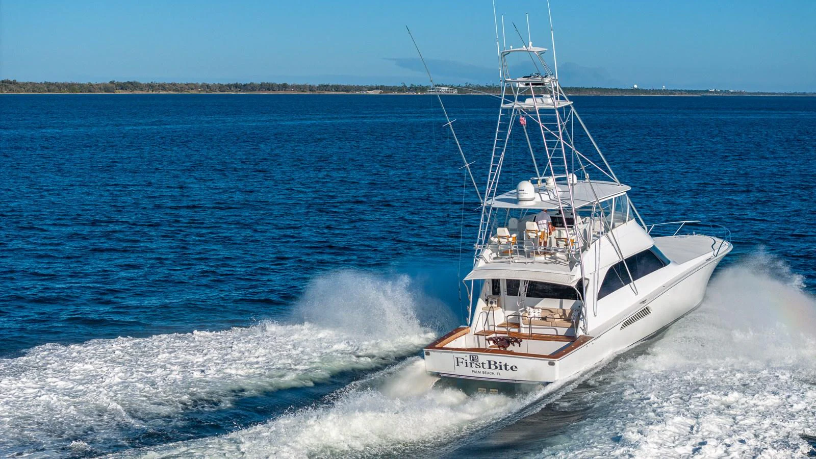 A sleek yacht cruises through the open water, leaving a trail of white wake behind. aboard FIRST BITE Yacht for Sale