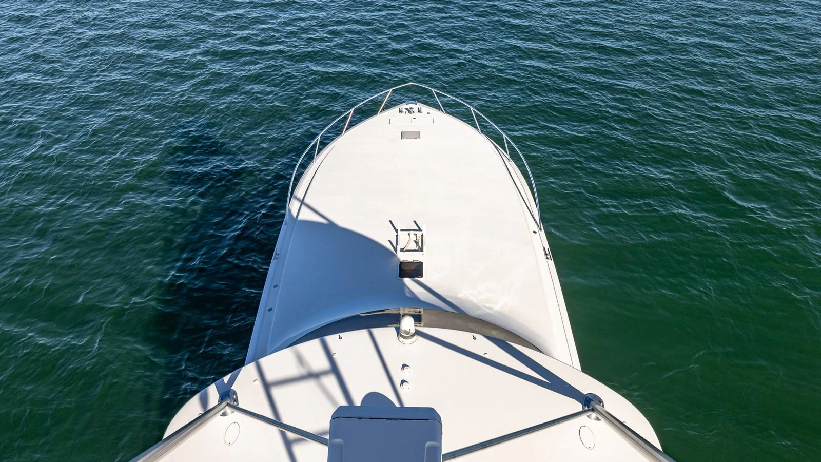 The bow of the yacht is seen from above, cutting through calm waters. aboard FIRST BITE Yacht for Sale