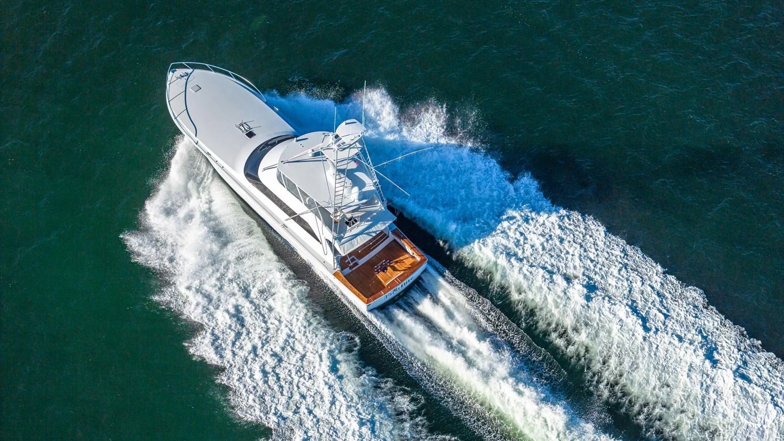 A sleek yacht cruises swiftly through the water, leaving a trail of white waves behind. aboard FIRST BITE Yacht for Sale