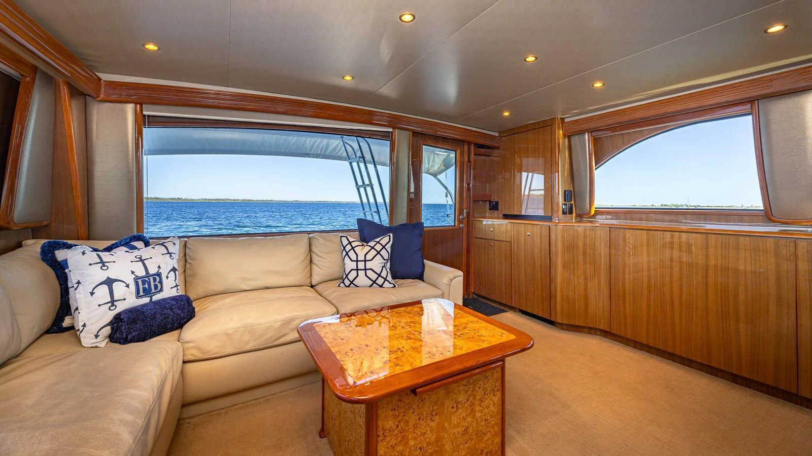The salon features plush seating and elegant wood finishes with a view of the ocean. aboard FIRST BITE Yacht for Sale