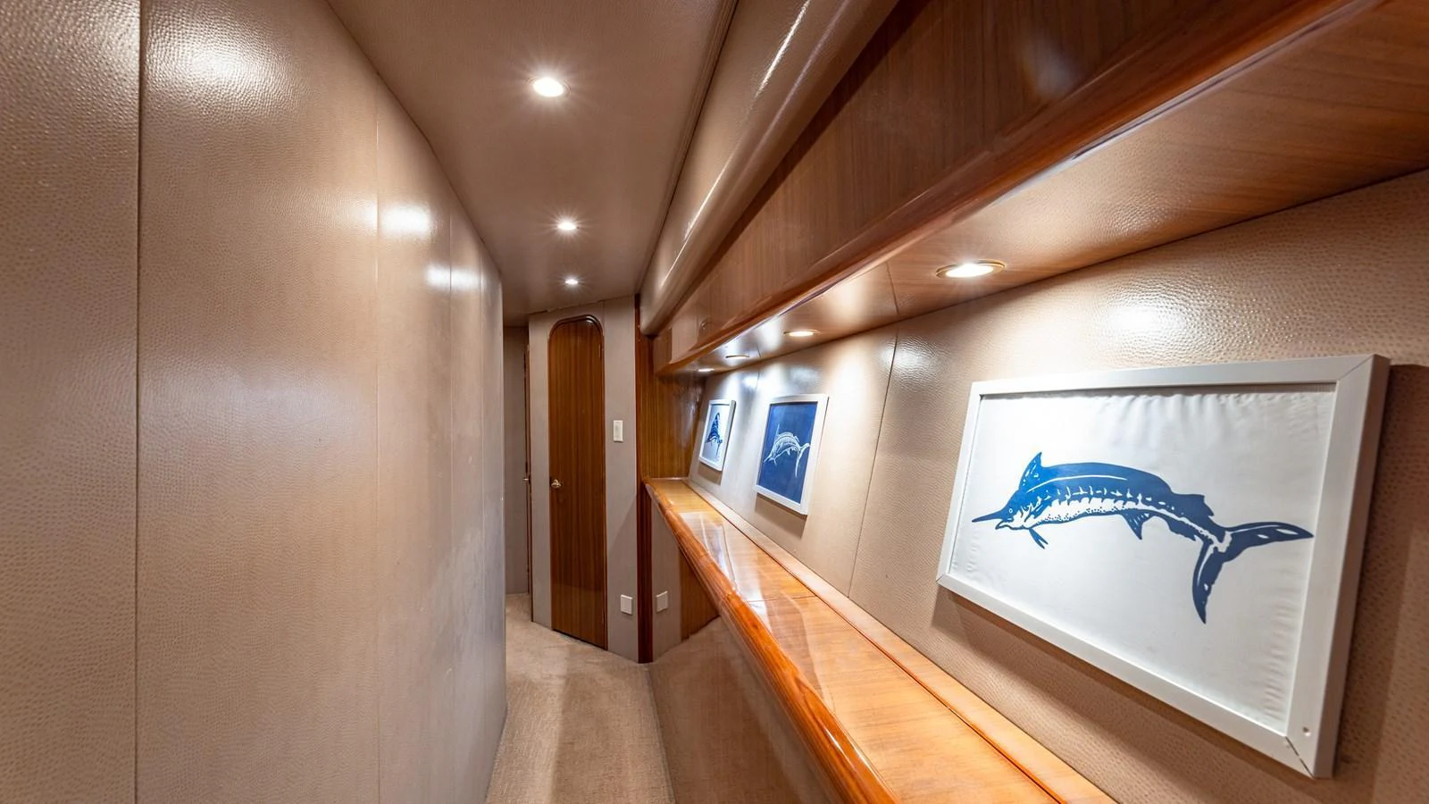 A sleek hallway with wooden accents and marine-themed artwork. aboard FIRST BITE Yacht for Sale