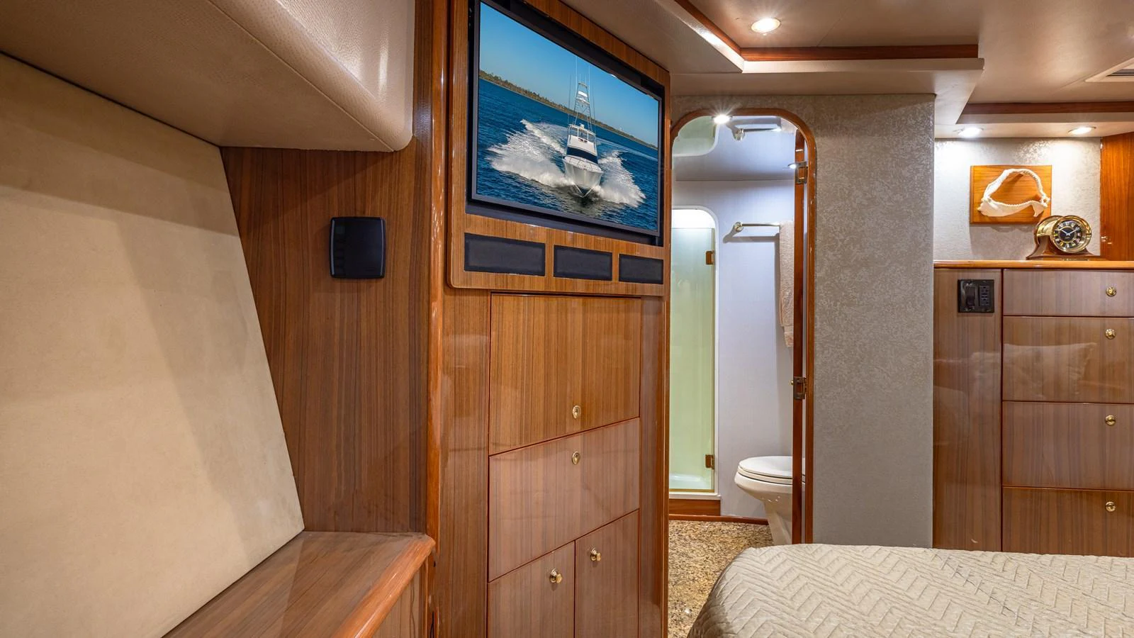 The stateroom features warm wood finishes, a mounted TV, and an ensuite bathroom. aboard FIRST BITE Yacht for Sale