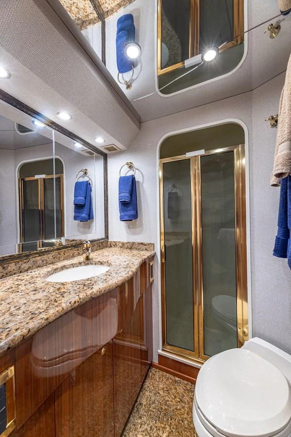 The yacht's bathroom features luxurious finishes with a granite countertop and gold accents. aboard FIRST BITE Yacht for Sale
