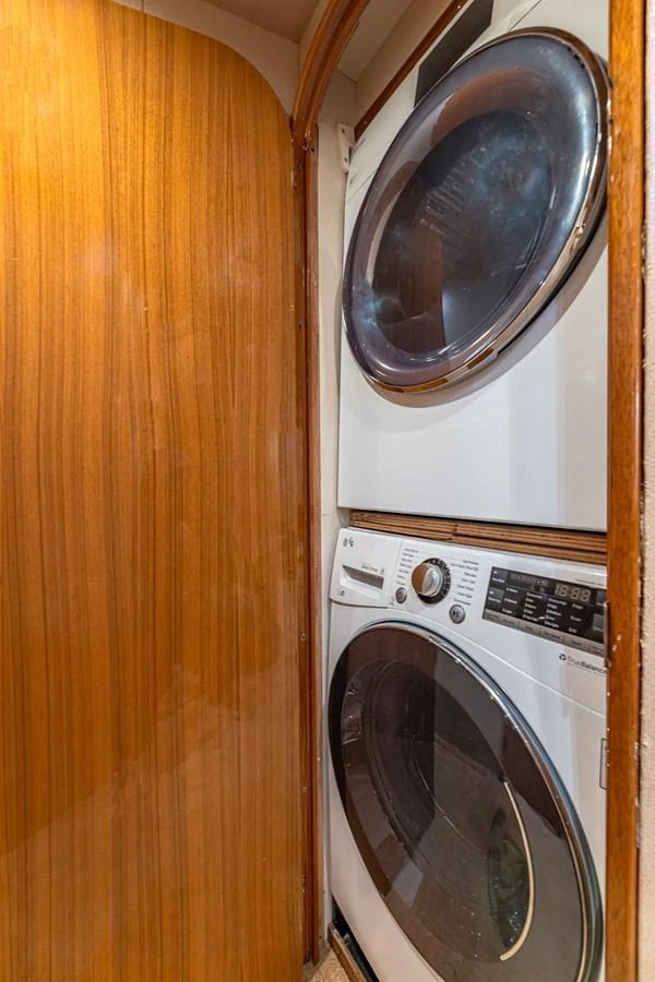 The yacht features a compact and efficient laundry area with a stacked washer and dryer. aboard FIRST BITE Yacht for Sale