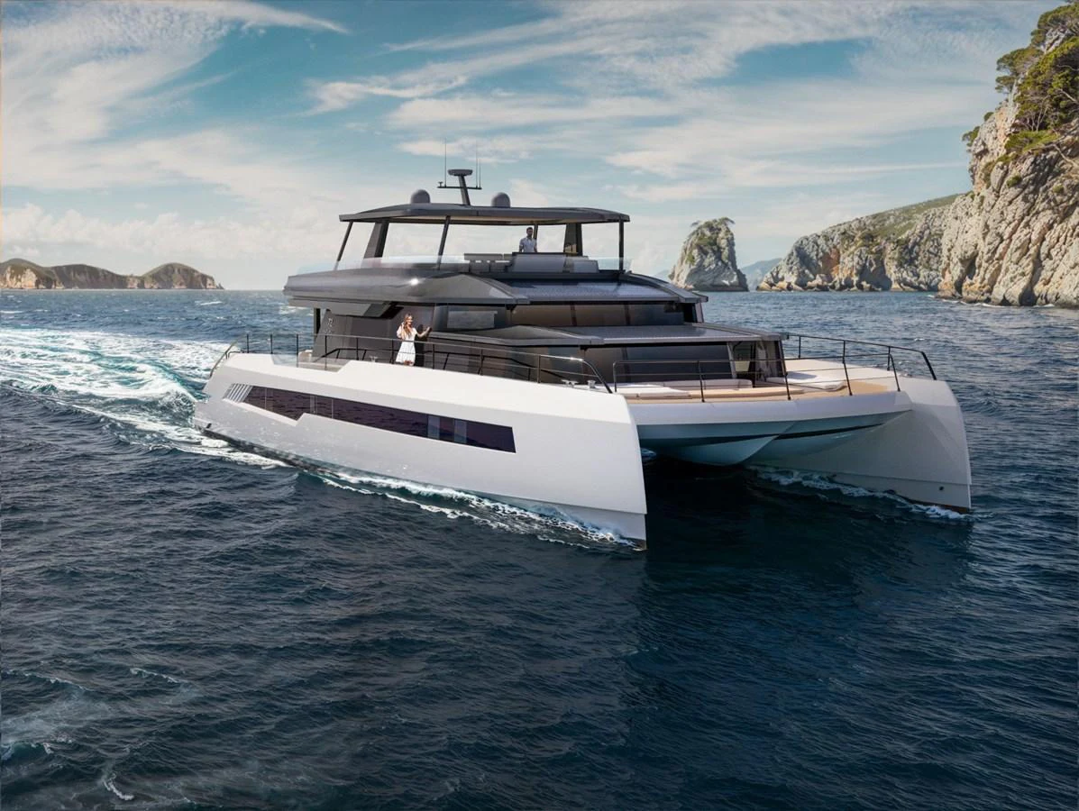 A sleek and modern catamaran yacht cruising through clear blue waters with scenic cliffs in the background. aboard CELESTIA 72 Yacht for Sale