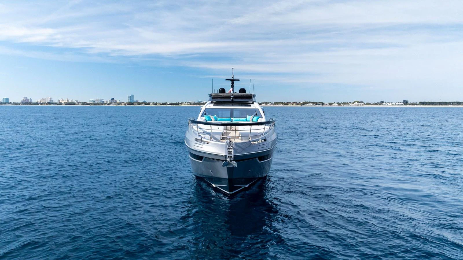 A sleek yacht is captured head-on, cruising on calm blue waters under a clear sky. aboard OCEAN'S SE7EN Yacht for Sale