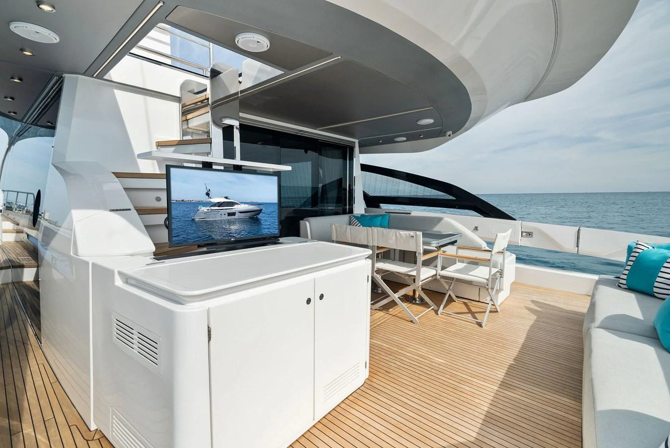 The aft deck features a spacious seating area with a dining table and a pop-up TV, perfect for outdoor entertainment. aboard OCEAN'S SE7EN Yacht for Sale
