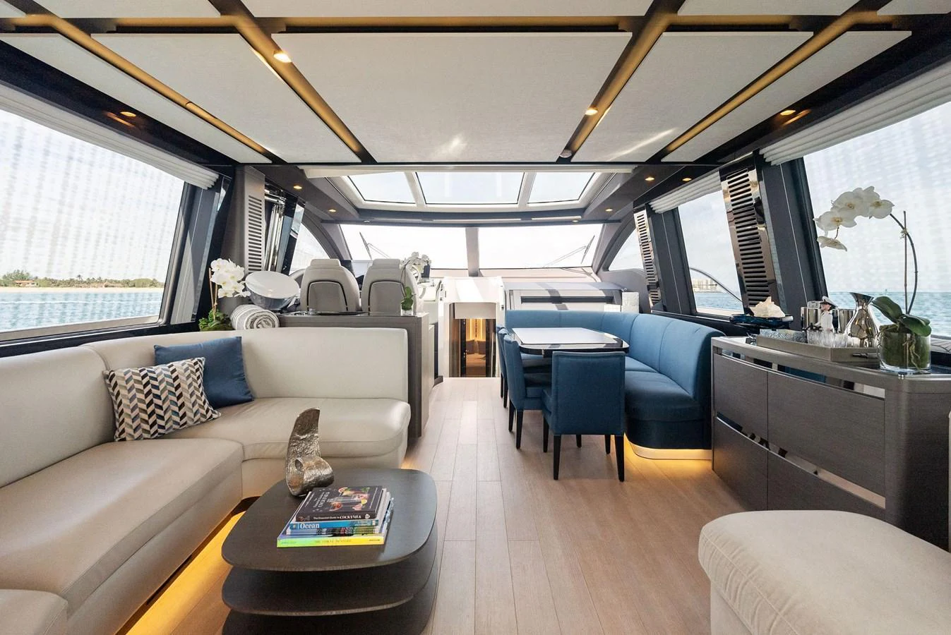 The yacht's salon features elegant seating, a dining area, and large windows for panoramic views. aboard OCEAN'S SE7EN Yacht for Sale