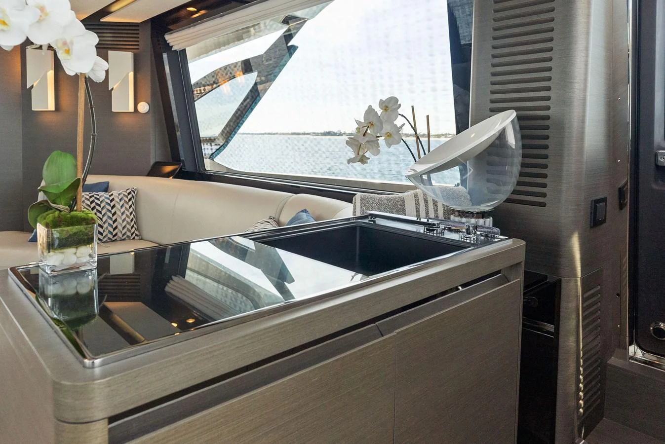 A modern and stylish interior space featuring a sleek countertop and comfortable seating with a view of the water. aboard OCEAN'S SE7EN Yacht for Sale