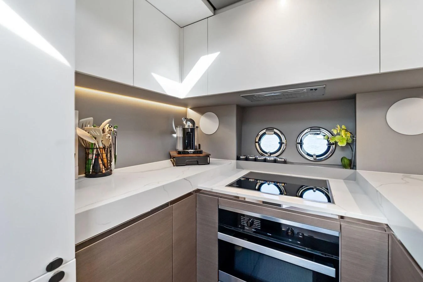 The modern galley features sleek cabinetry, a built-in stove, and porthole windows for natural light. aboard OCEAN'S SE7EN Yacht for Sale