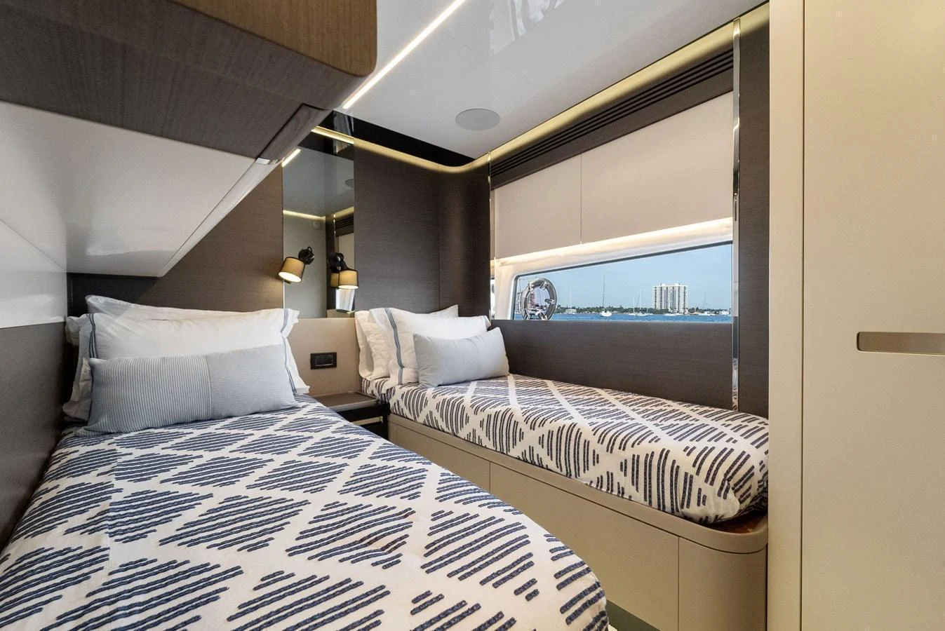 The guest stateroom features twin beds with modern bedding and a large window providing a view of the water. aboard OCEAN'S SE7EN Yacht for Sale