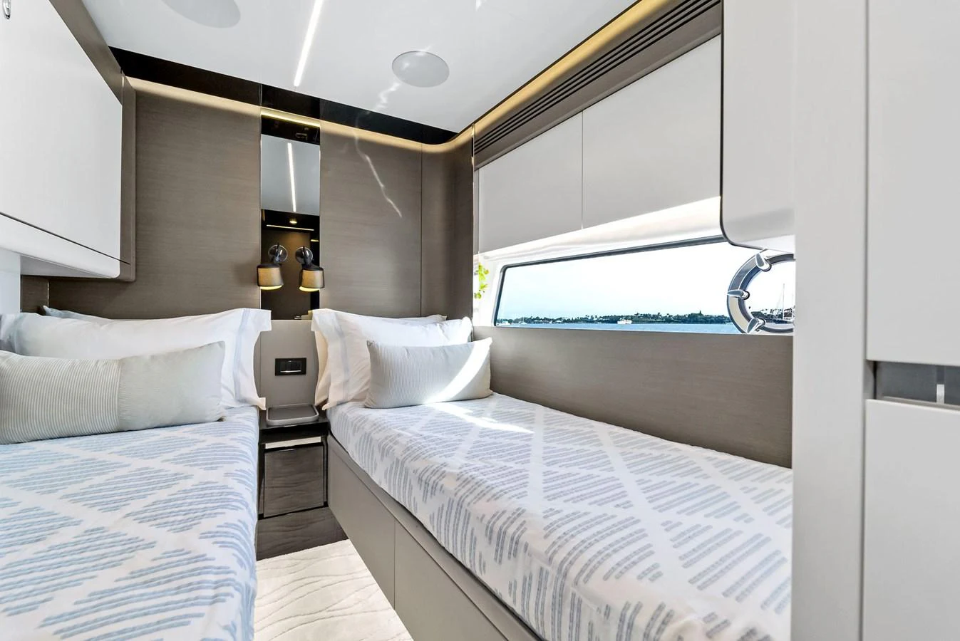 The guest stateroom features twin beds with a modern and elegant design, offering a serene view through the window. aboard OCEAN'S SE7EN Yacht for Sale