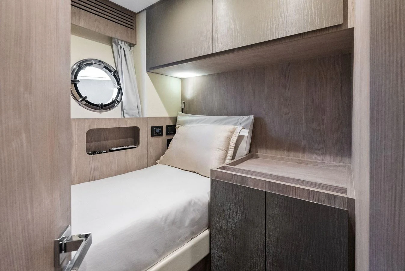 A cozy cabin with a single bed and modern wooden furnishings. aboard OCEAN'S SE7EN Yacht for Sale