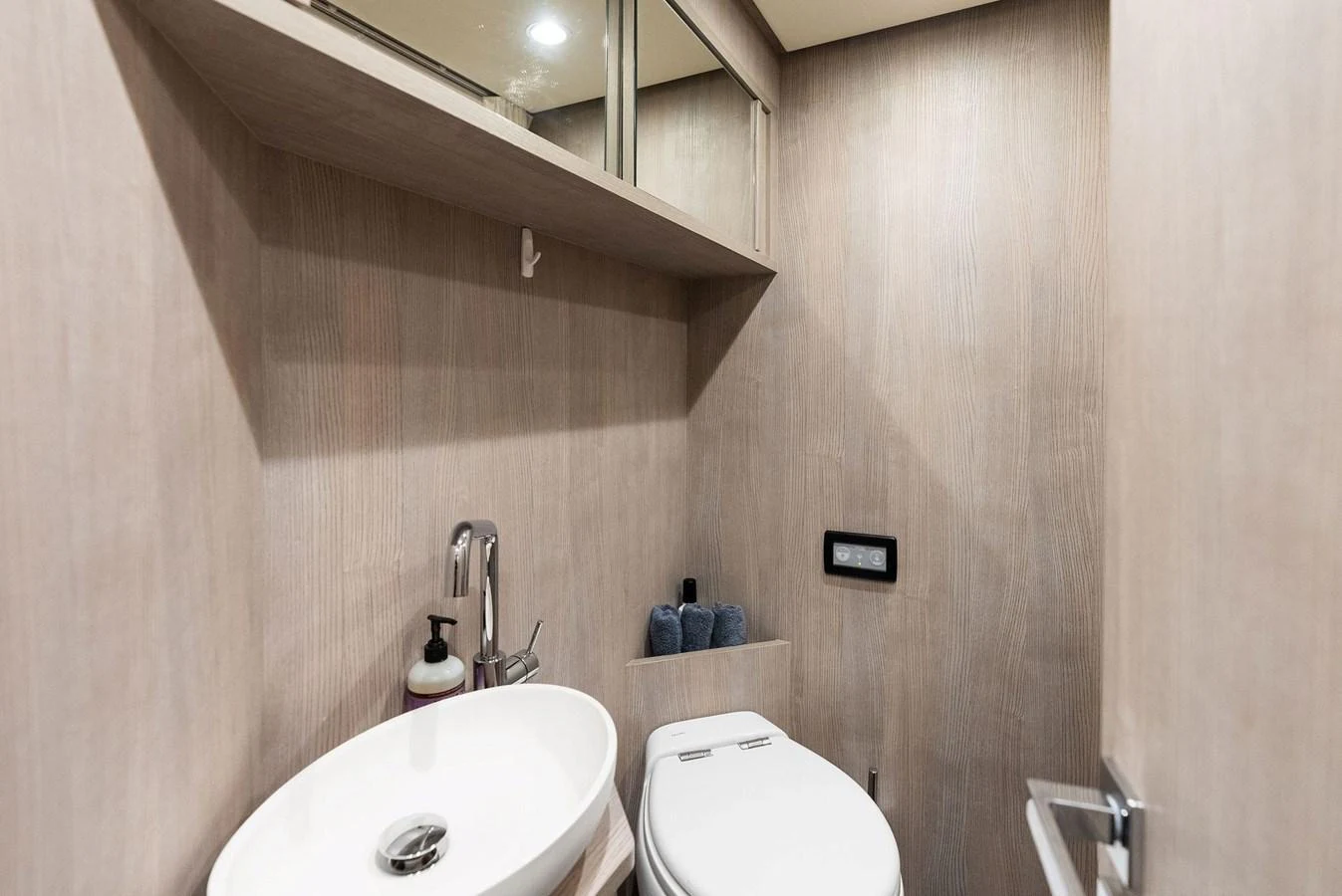 The yacht's head features a modern sink and toilet with sleek wooden paneling. aboard OCEAN'S SE7EN Yacht for Sale