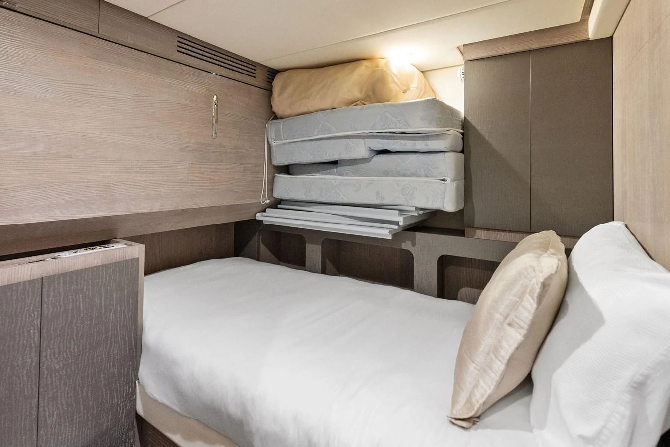 The guest cabin features a cozy single bed with additional bedding stored above. aboard OCEAN'S SE7EN Yacht for Sale