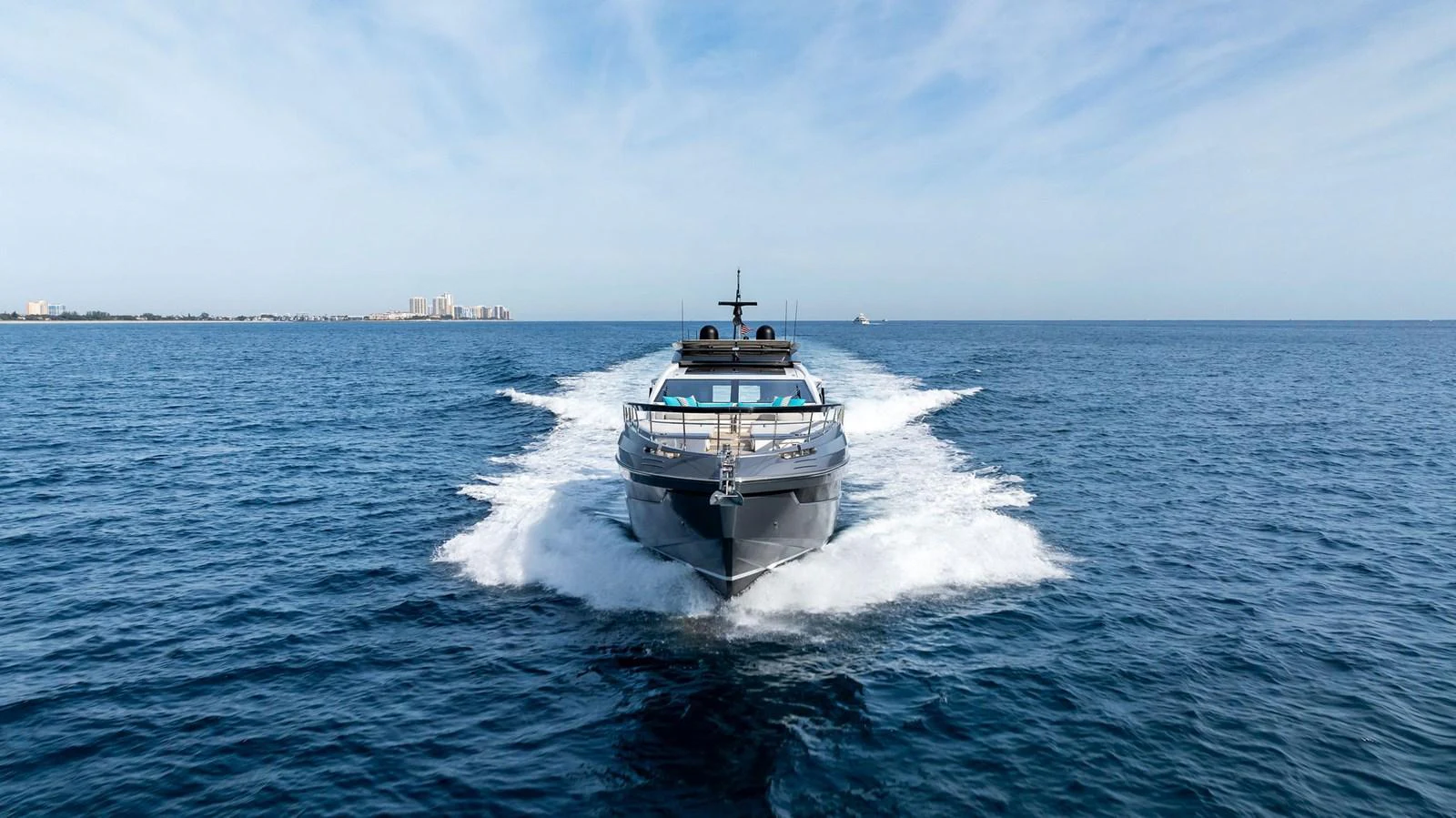 A sleek yacht cruises forward on open waters under a clear blue sky. aboard OCEAN'S SE7EN Yacht for Sale