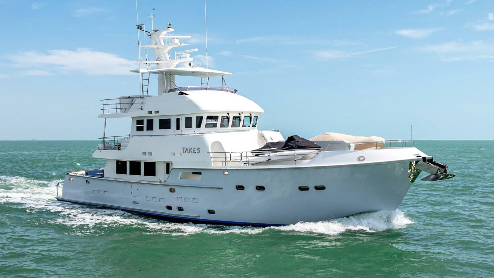 A sleek and modern yacht cruises smoothly on the open sea under a clear blue sky. aboard TAKE 5 Yacht for Sale