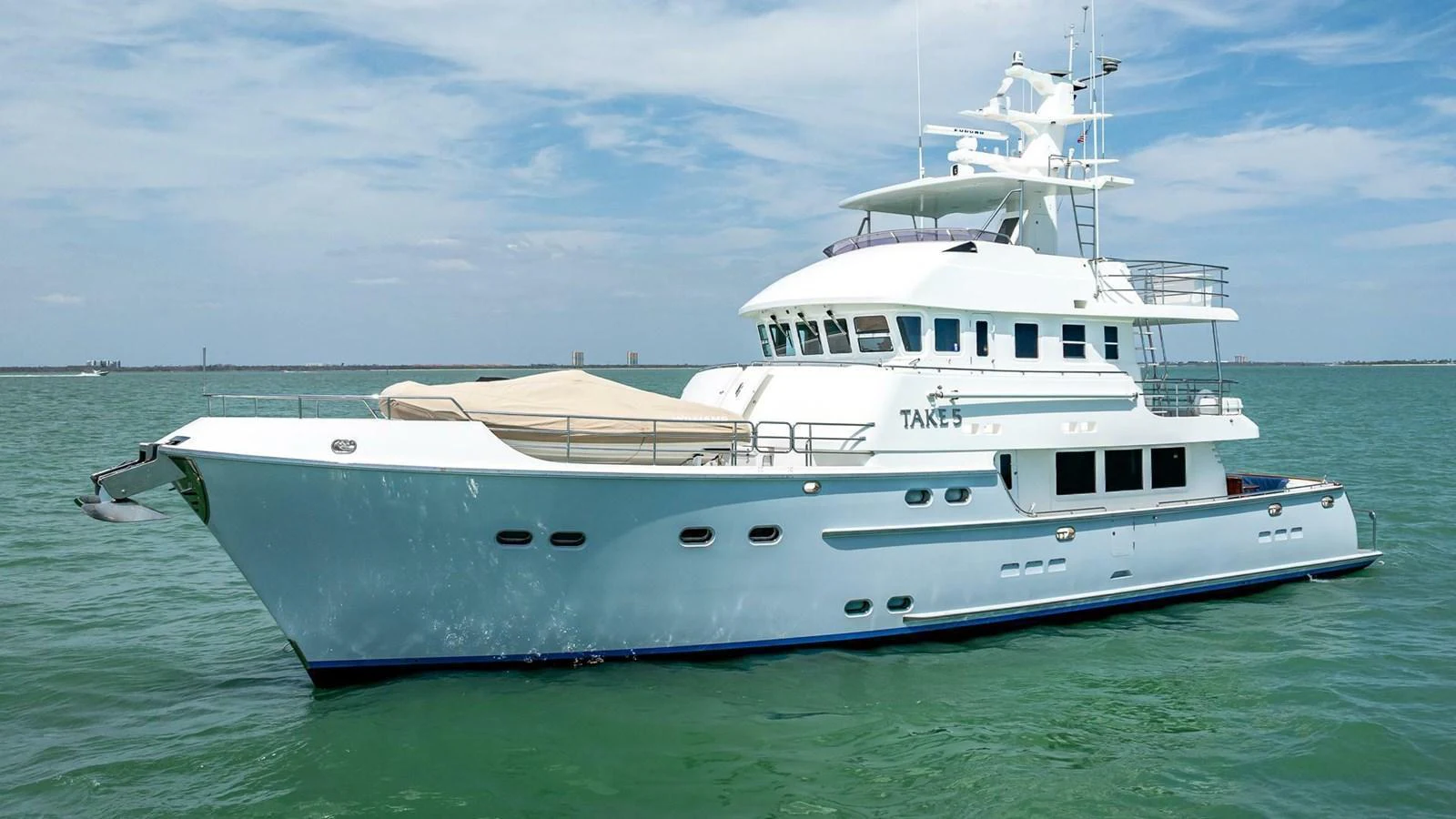 A sleek and modern yacht cruising on calm waters under a clear sky. aboard TAKE 5 Yacht for Sale