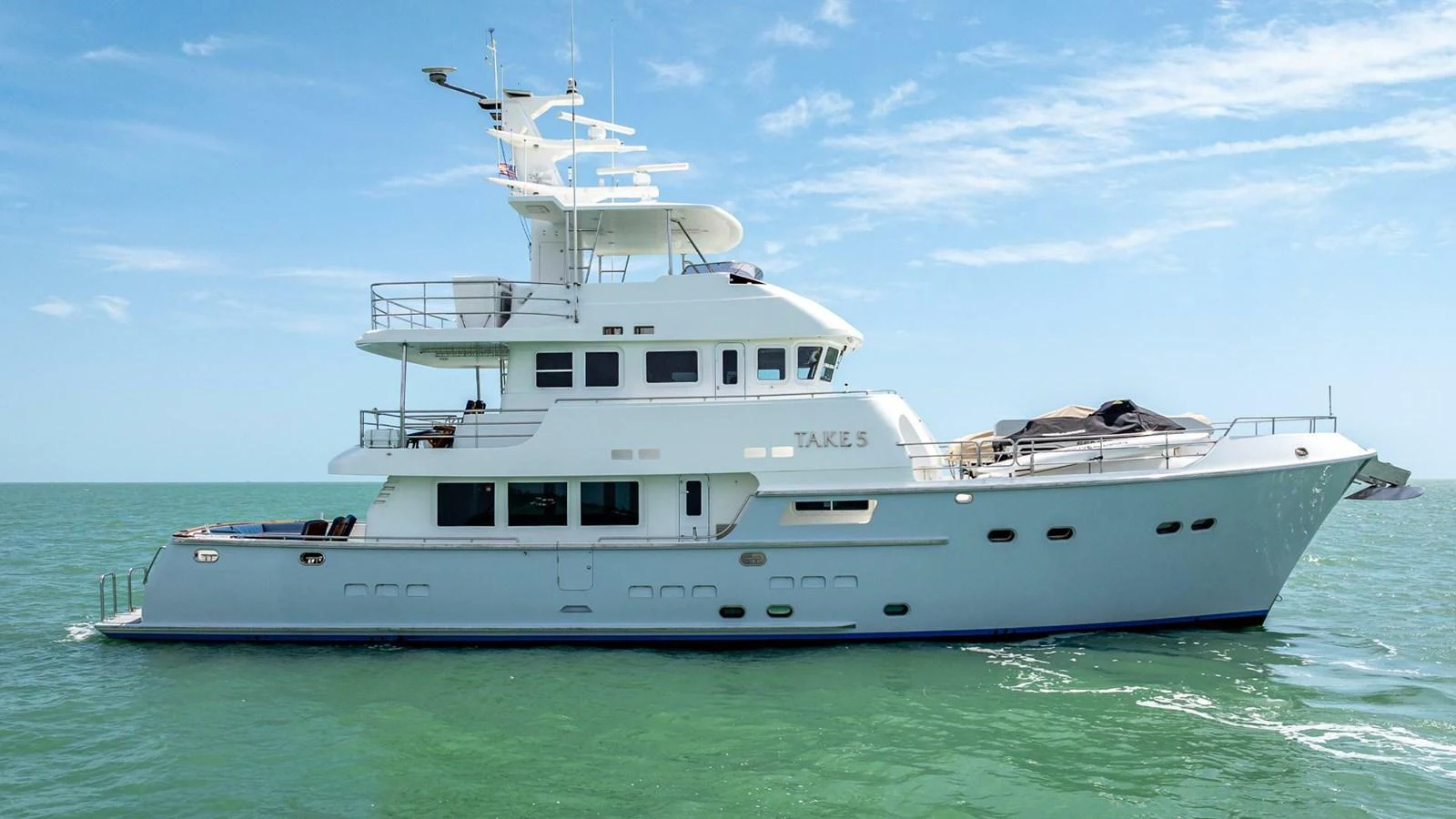A sleek and modern yacht cruising on calm waters under a clear blue sky. aboard TAKE 5 Yacht for Sale