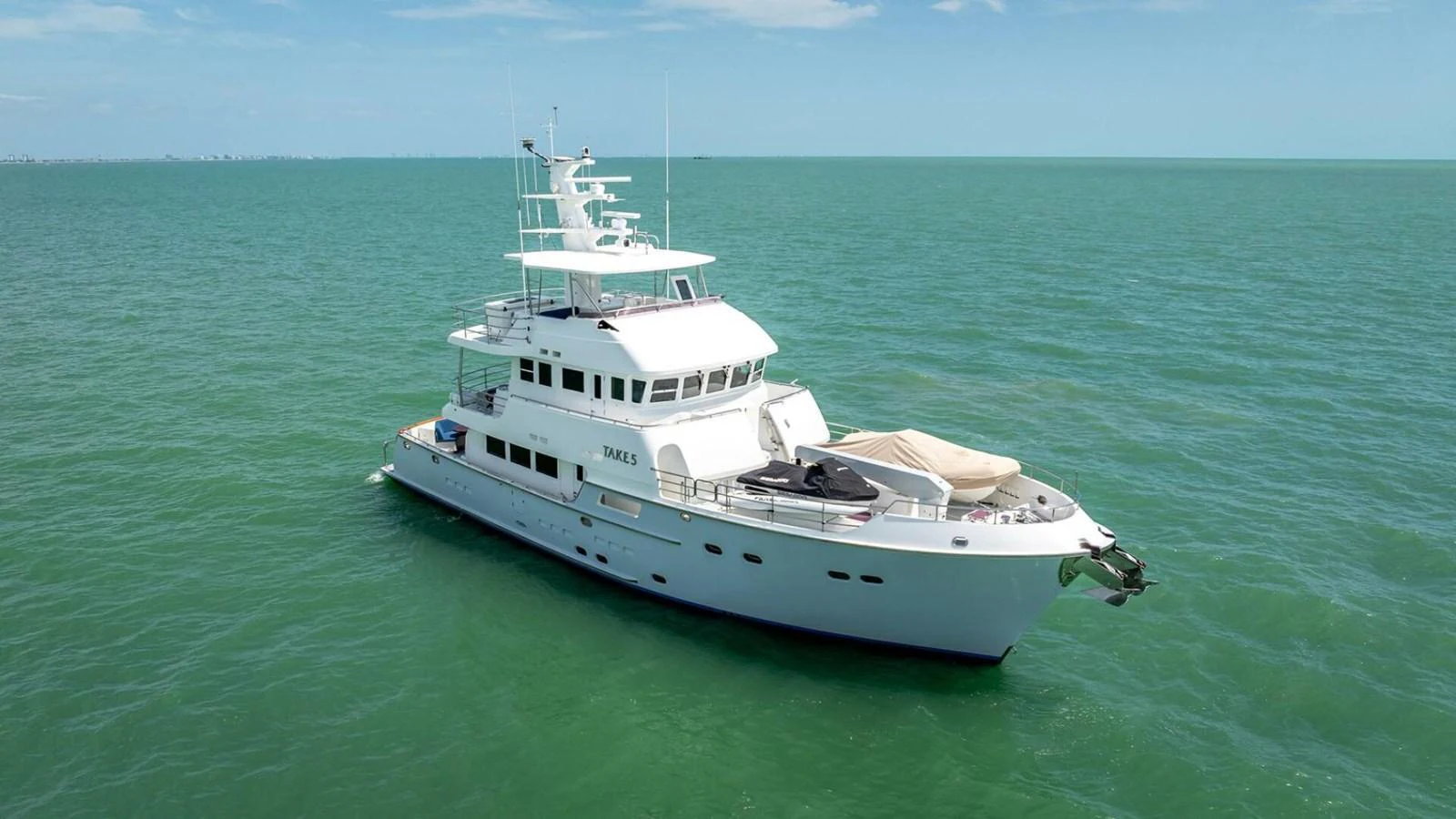 A stunning white yacht glides gracefully on calm, turquoise waters under a clear blue sky. aboard TAKE 5 Yacht for Sale