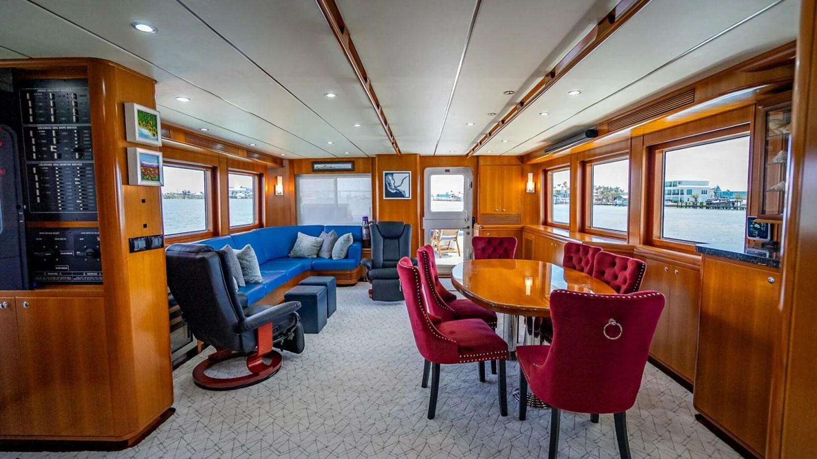The salon features a comfortable seating area with vibrant red chairs and large windows offering panoramic views. aboard TAKE 5 Yacht for Sale
