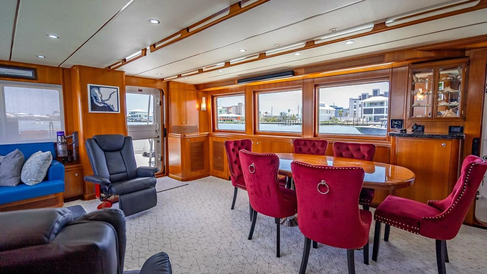The yacht's salon features a spacious and elegant dining area with plush red chairs and large windows offering scenic views. aboard TAKE 5 Yacht for Sale