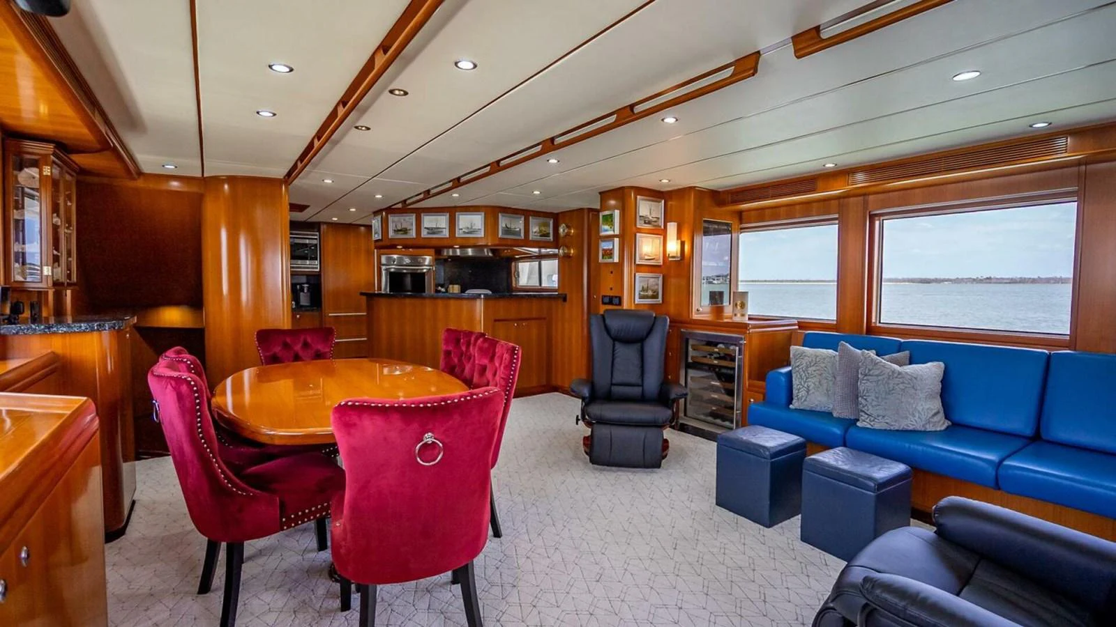 The salon features luxurious seating with vibrant red chairs and a comfortable blue sofa, creating a warm and inviting atmosphere. aboard TAKE 5 Yacht for Sale