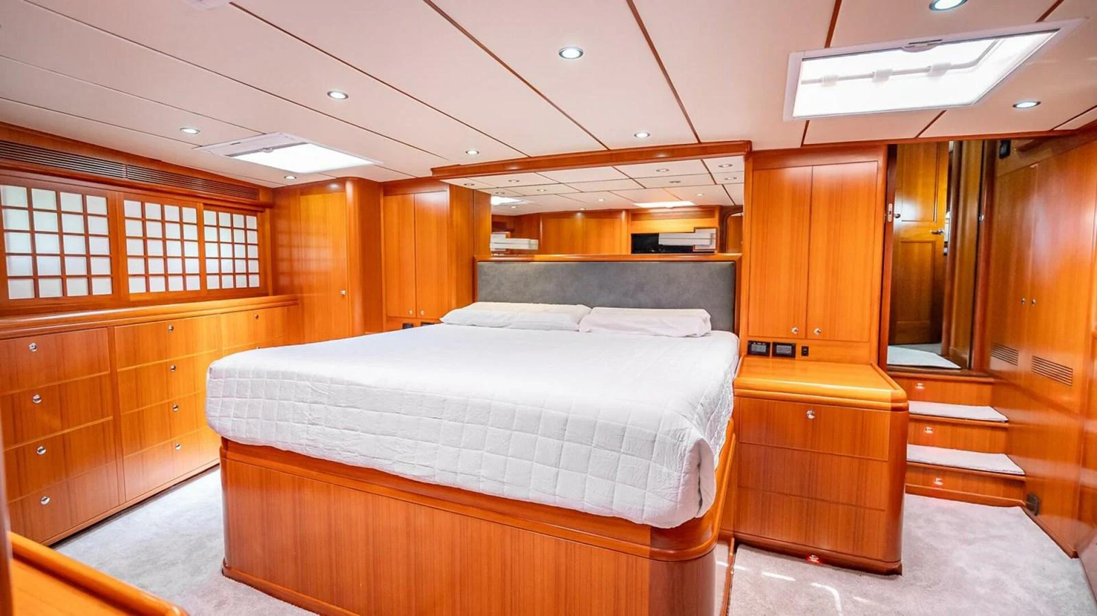 The master stateroom features a spacious bed with warm wooden cabinetry and ample lighting. aboard TAKE 5 Yacht for Sale
