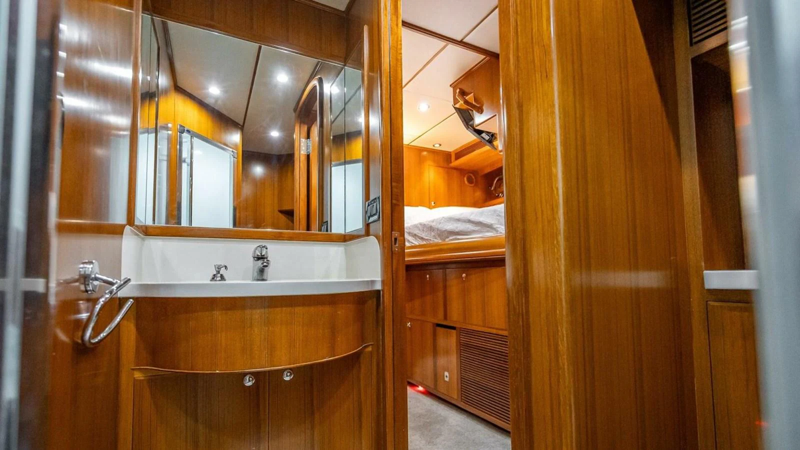 The image showcases a well-appointed bathroom and adjacent cabin with warm wooden finishes. aboard TAKE 5 Yacht for Sale