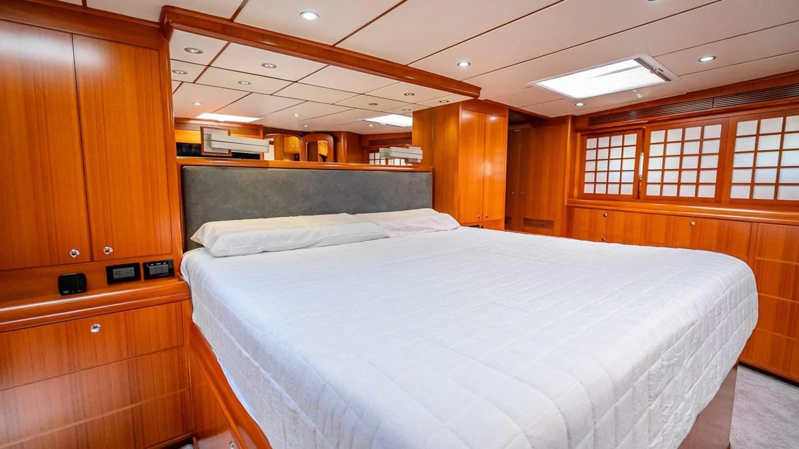 The master stateroom features a spacious bed with elegant wood paneling and ample storage. aboard TAKE 5 Yacht for Sale