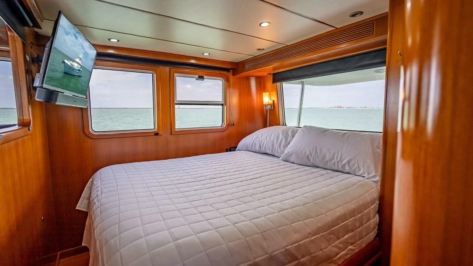 The cozy stateroom features a large bed with a view of the sea through multiple windows. aboard TAKE 5 Yacht for Sale