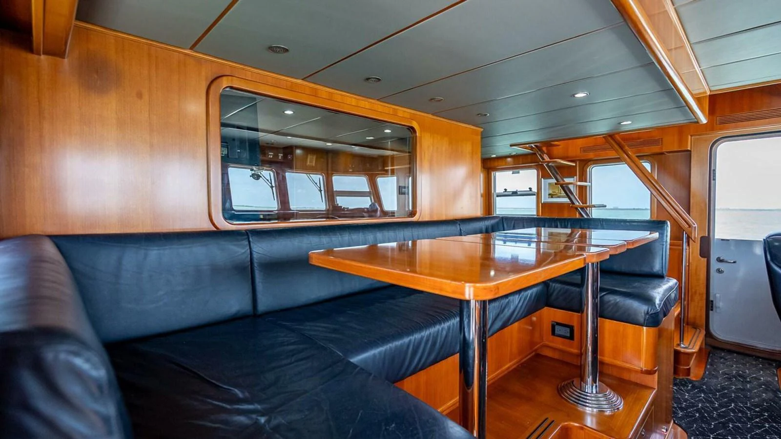 The saloon features a comfortable seating area with a polished wooden table and large windows for natural light. aboard TAKE 5 Yacht for Sale